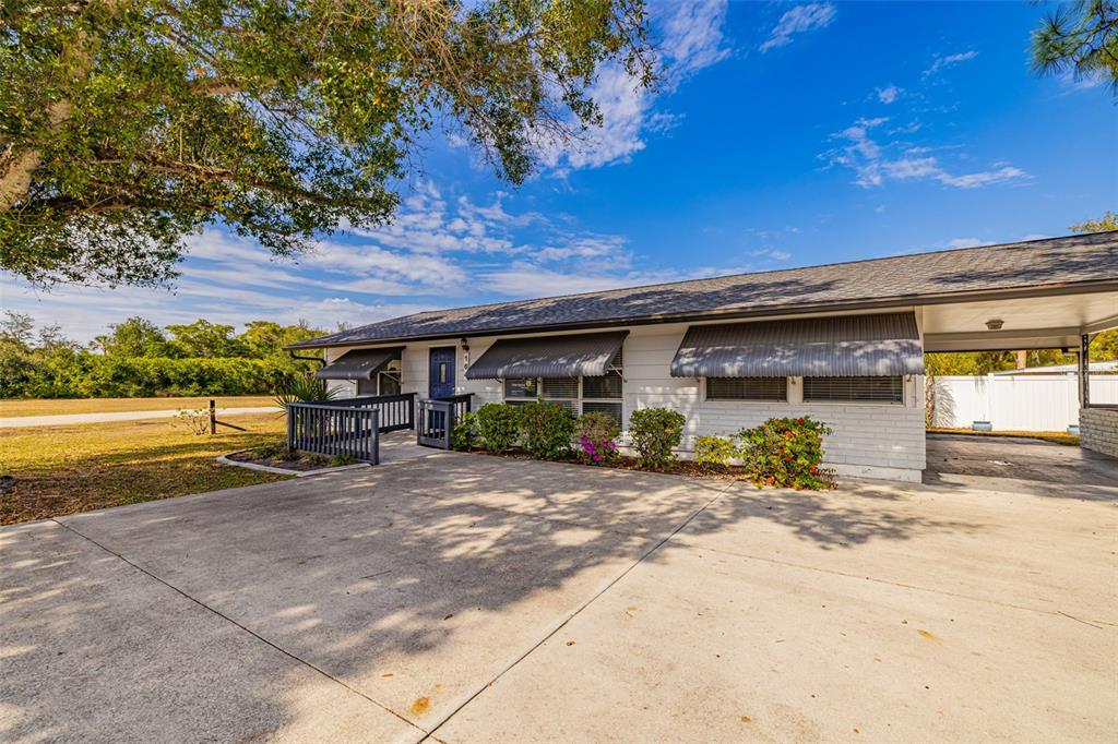 A single-story house with a white exterior, gray awnings, and a concrete driveway — 164 PONDELLA ROAD, NORTH FORT MYERS, FL