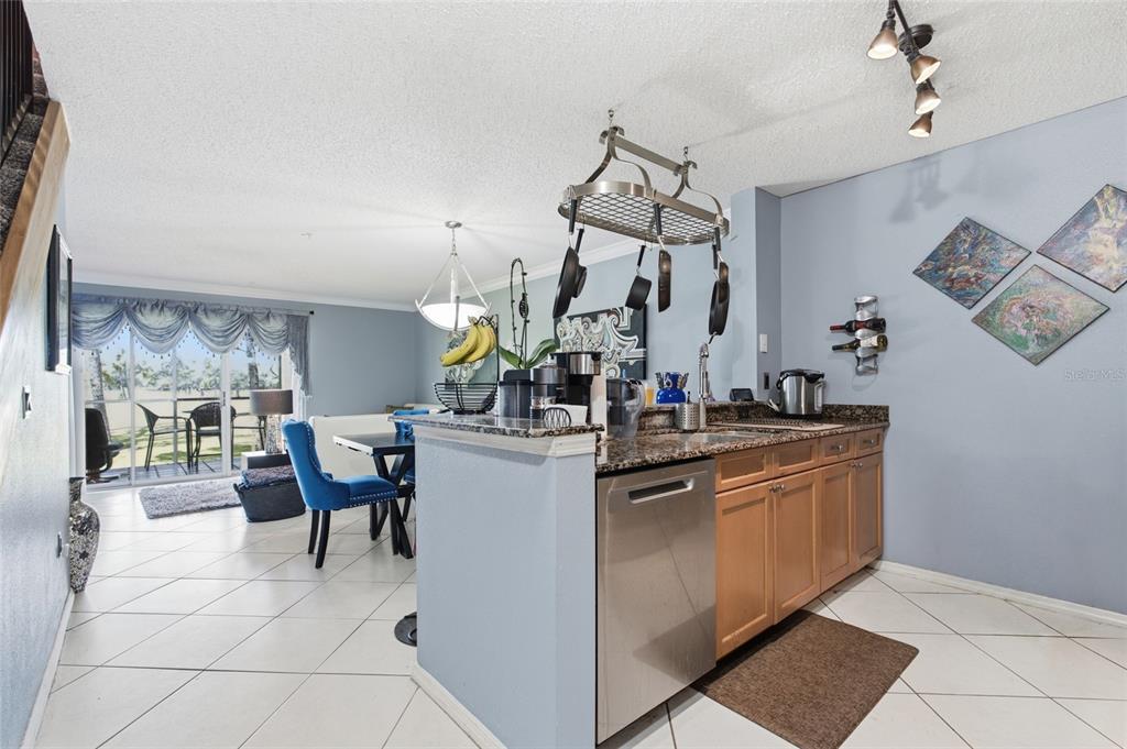 A kitchen with light wood cabinets, granite countertops, and a hanging pot rack — 2400 FEATHER SOUND DRIVE UNIT 313, CLEARWATER, FL