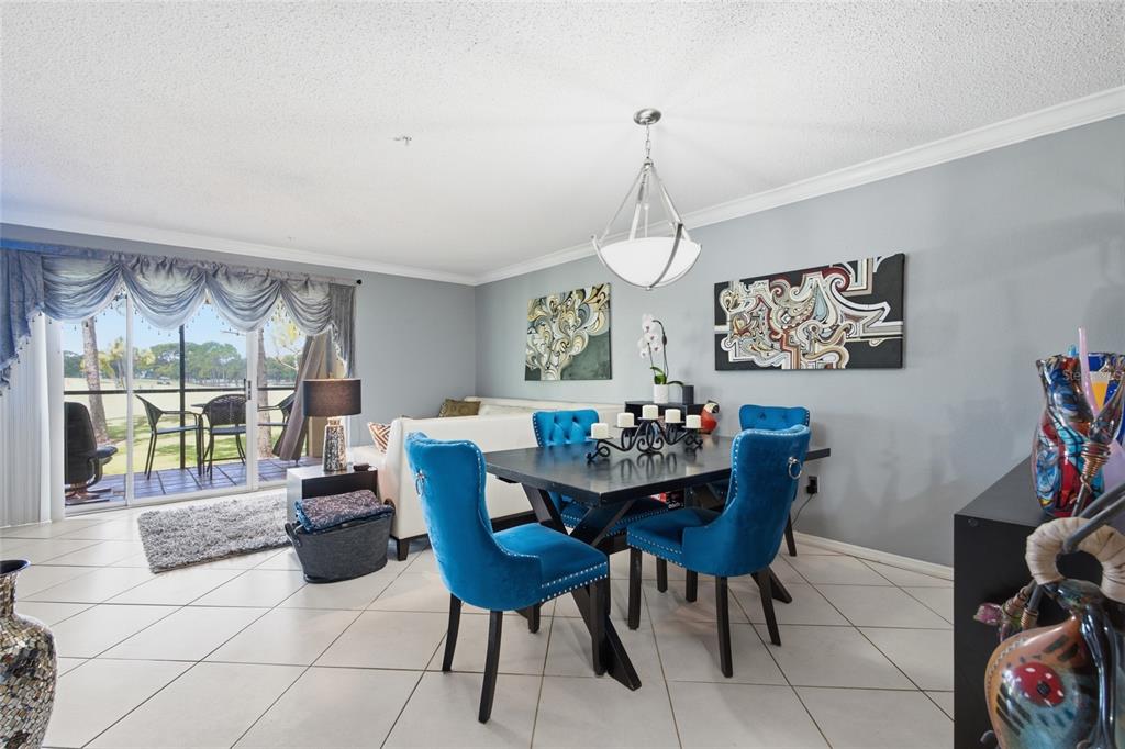 A dining area with blue velvet chairs and a black table sits near a living room — 2400 FEATHER SOUND DRIVE UNIT 313, CLEARWATER, FL