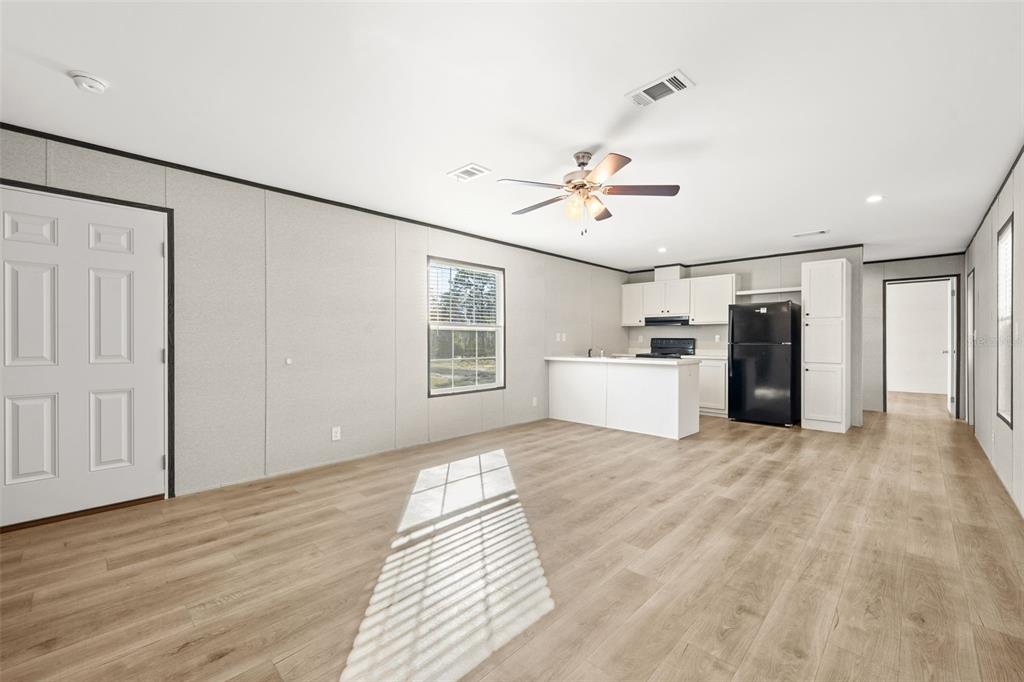An open-concept living room and kitchen with light wood flooring and white cabinetry — 5370 NE 108TH TERRACE, BRONSON, FL