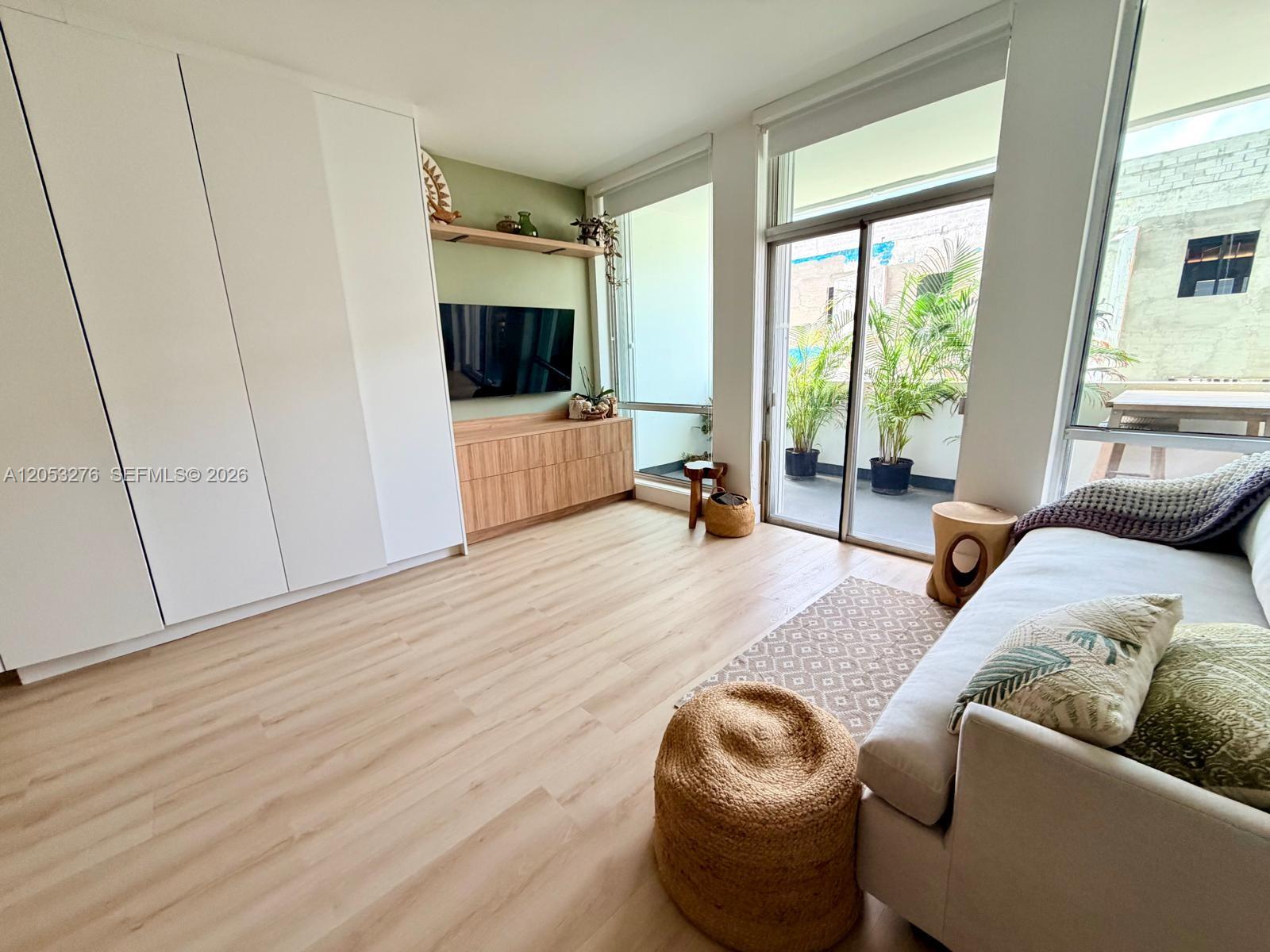 A living room features light wood flooring, a green accent wall, and a balcony view — 700 Biltmore Way # 308, Coral Gables FL 33134, CORAL GABLES, FL