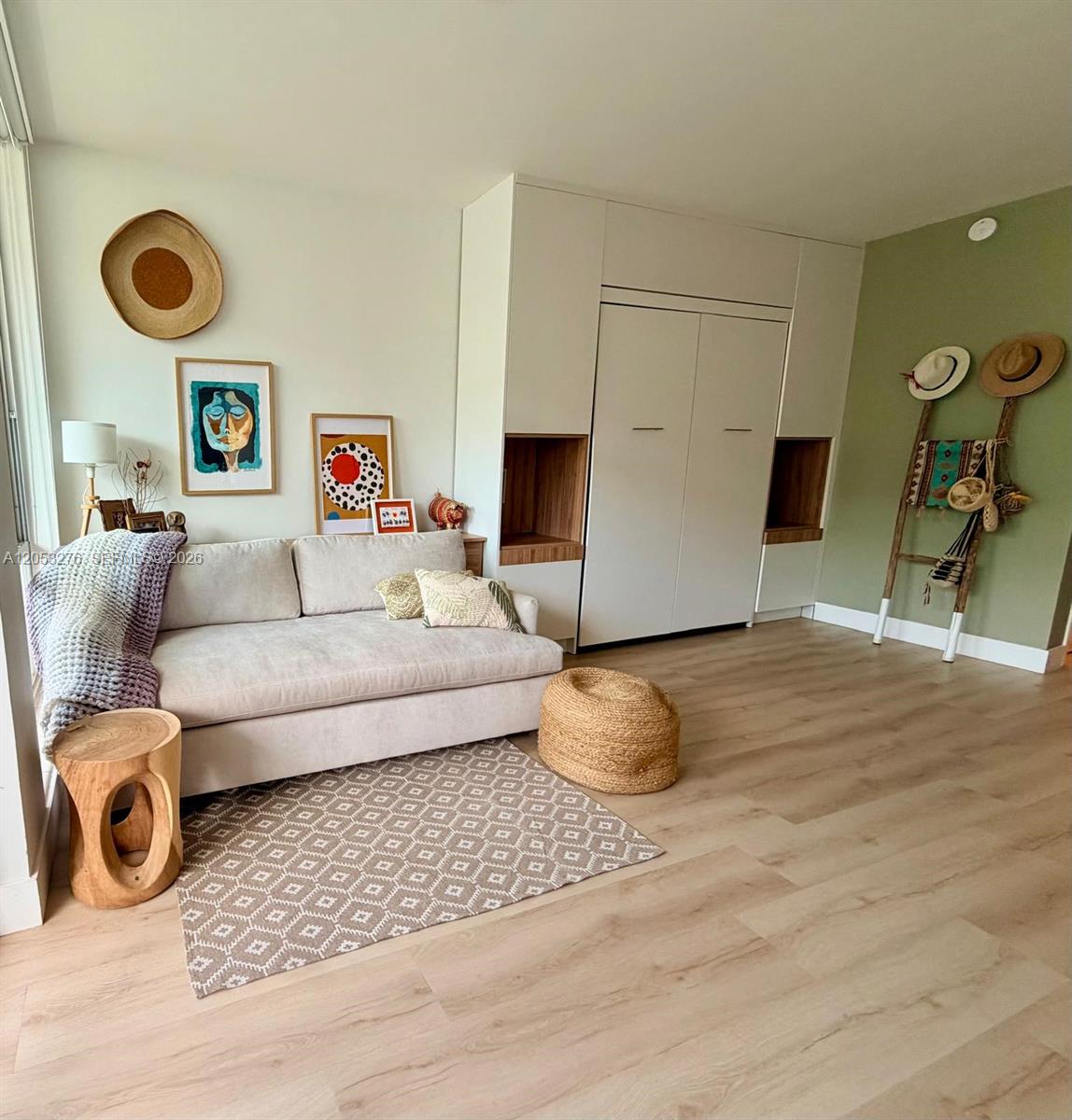 A living room features a sofa, a wall-mounted Murphy bed unit, and light wood flooring — 700 Biltmore Way # 308, Coral Gables FL 33134, CORAL GABLES, FL