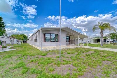 A single-story manufactured home with light gray siding and a covered front porch — 35151 COLONY HILLS DRIVE, ZEPHYRHILLS, FL