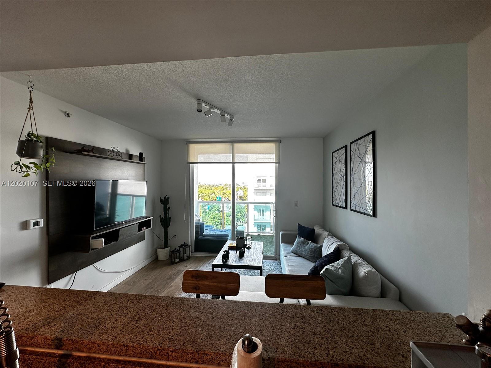 A living room features a wall-mounted television, a sofa, and a balcony with outdoor seating — 1723 SW 2nd Ave # 704, Miami FL 33129, MIAMI, FL