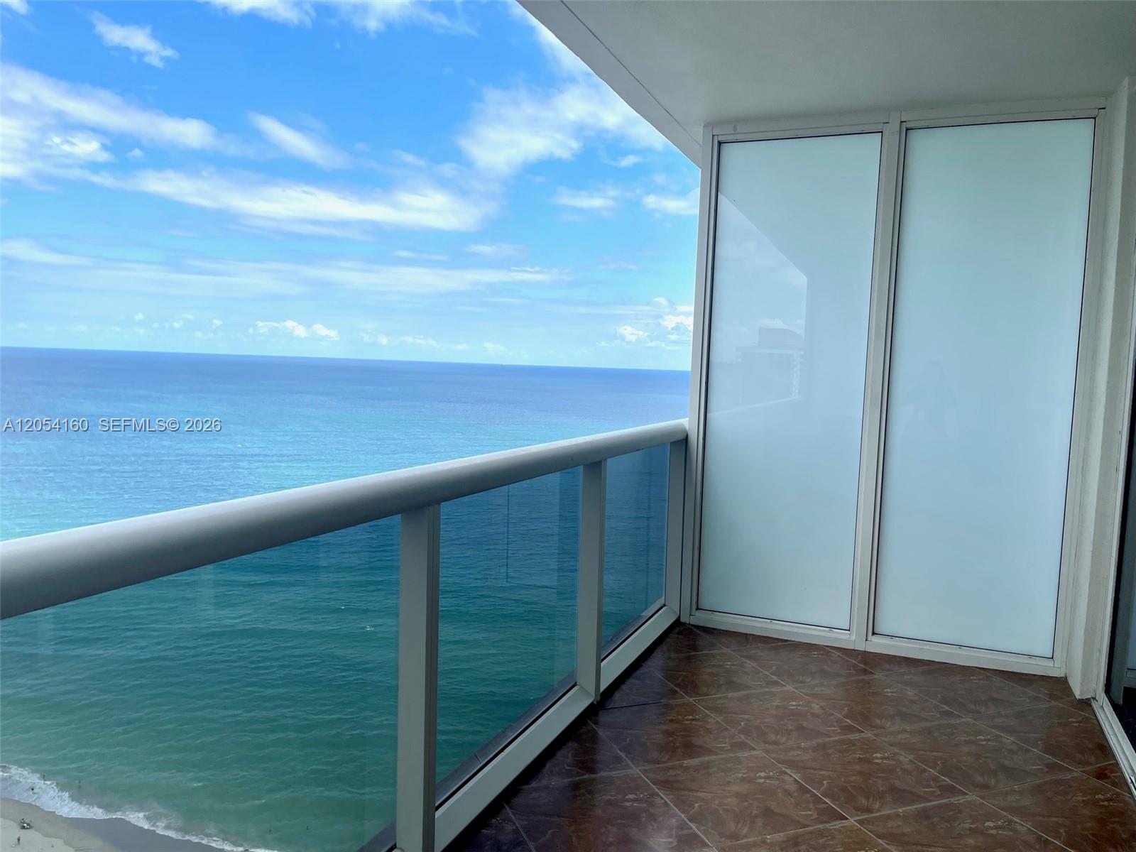 A balcony with tiled flooring and a glass railing overlooks the ocean — 1830 S Ocean Dr # 3309, Hallandale Beach FL 33009, HALLANDALE BEACH, FL