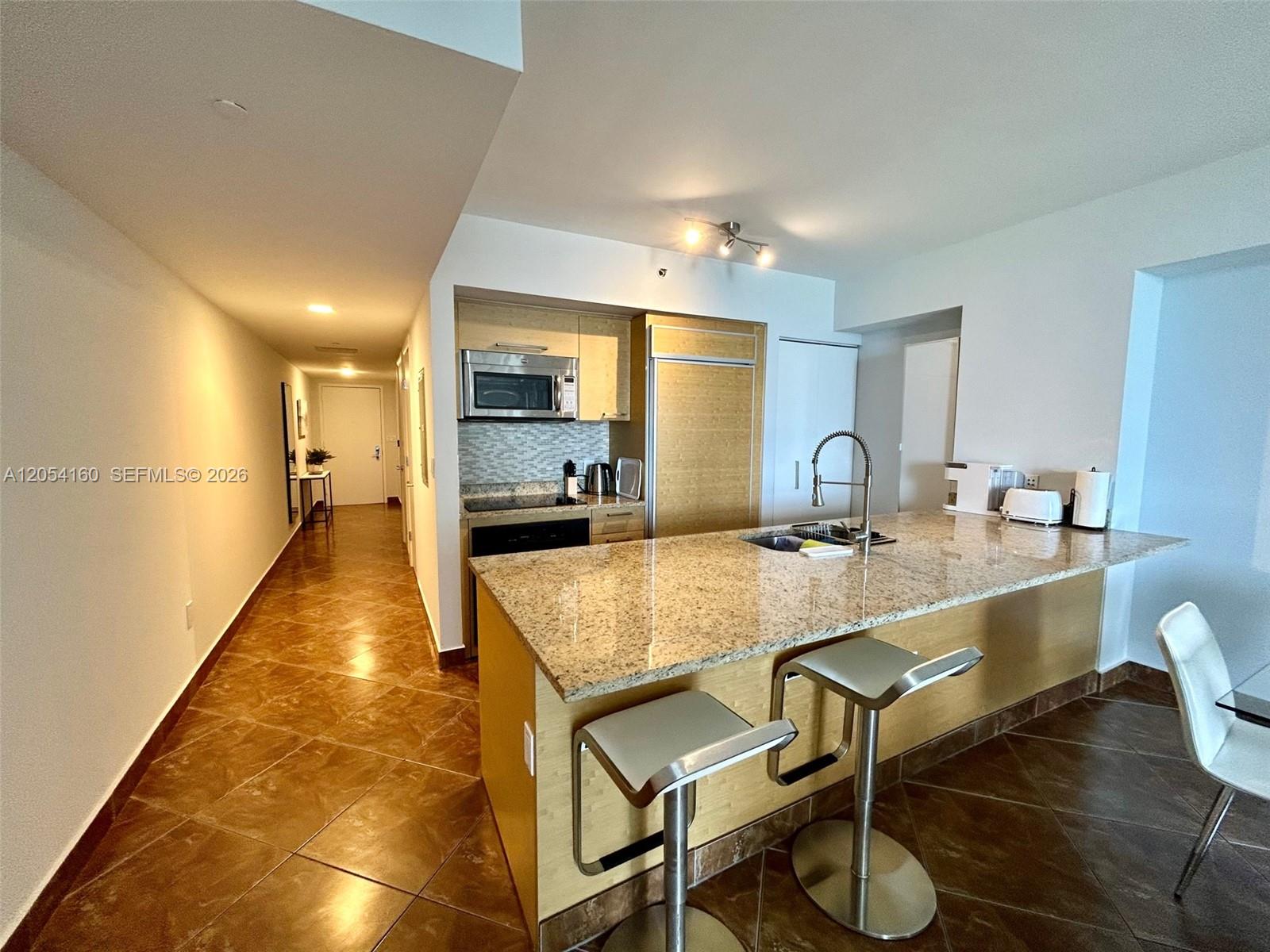 A kitchen features a granite-topped island with bar stools and light wood cabinetry — 1830 S Ocean Dr # 3309, Hallandale Beach FL 33009, HALLANDALE BEACH, FL