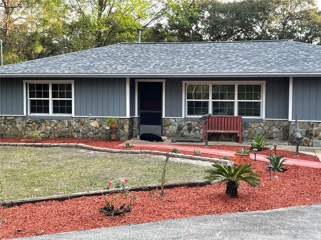 A single-story house with gray vertical siding, stone veneer, and a red walkway — 4540 W SANDY HILL STREET, LECANTO, FL