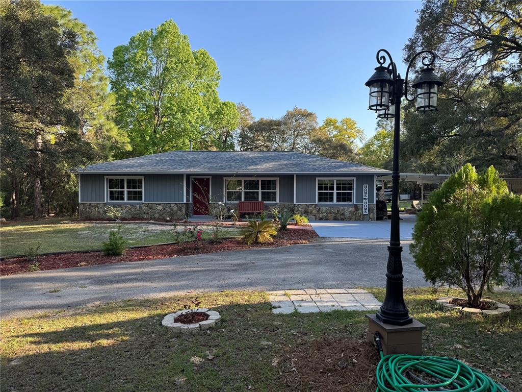 A single-story house with gray siding, stone accents, and a front yard with a lamp post — 4540 W SANDY HILL STREET, LECANTO, FL