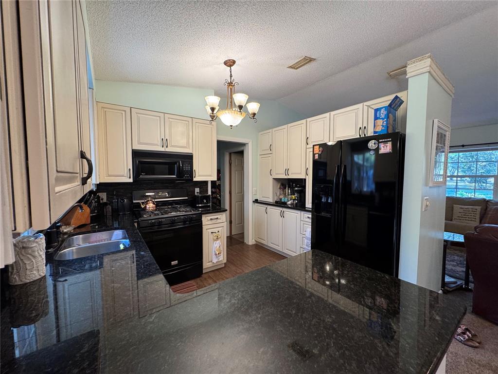 A kitchen with white cabinets, black appliances, and dark granite countertops — 4540 W SANDY HILL STREET, LECANTO, FL