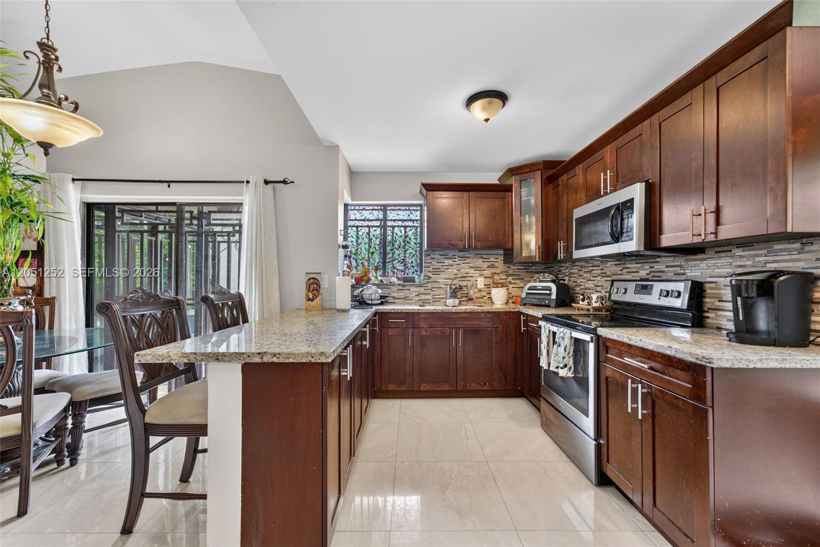 A kitchen features dark wood cabinets, granite countertops, stainless steel appliances, and tile flooring — 12422 SW 199th St, Miami FL 33177, MIAMI, FL