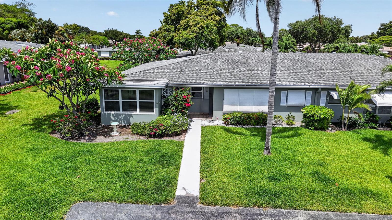 An exterior view of a single-story residential building with a gray roof and green lawn — 912 South Drive # A, Delray Beach FL 33445, DELRAY BEACH, FL