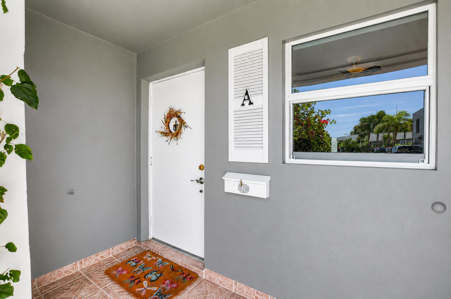 A gray exterior entryway features a white door with a wreath, a mailbox, and window — 912 South Drive # A, Delray Beach FL 33445, DELRAY BEACH, FL
