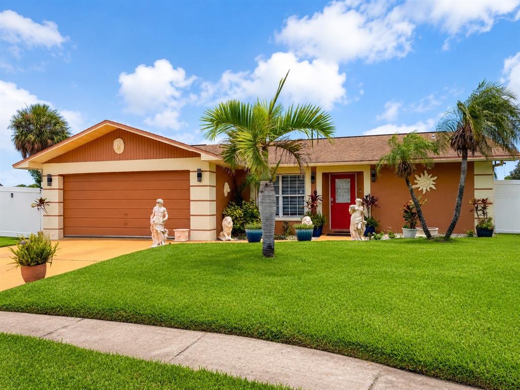 A single-story house with a brown garage, red front door, and statues in the yard — 3513 WESTMINISTER COURT, HOLIDAY, FL