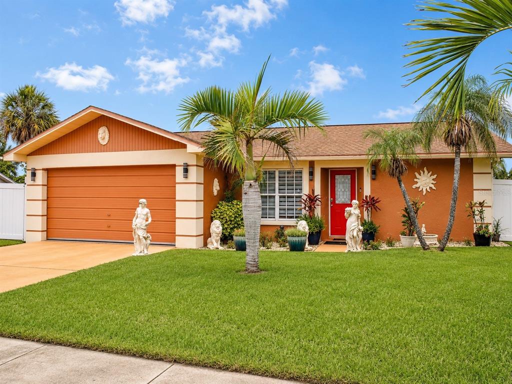 A single-story house with an orange exterior, a red front door, and a two-car garage — 3513 WESTMINISTER COURT, HOLIDAY, FL