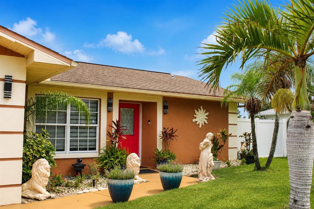 A single-story house with a red front door, lion statues, and palm trees in the yard — 3513 WESTMINISTER COURT, HOLIDAY, FL