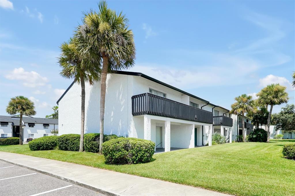 A white two-story apartment building with black railings and palm trees on a grassy lawn — 4309 N SEMORAN BOULEVARD UNIT 2, ORLANDO, FL