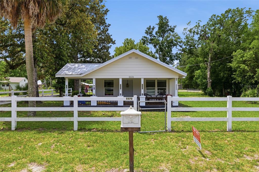 A single-story house with a front porch sits behind a white fence and mailbox — 5570 NAVARRE AVENUE, HAMPTON, FL