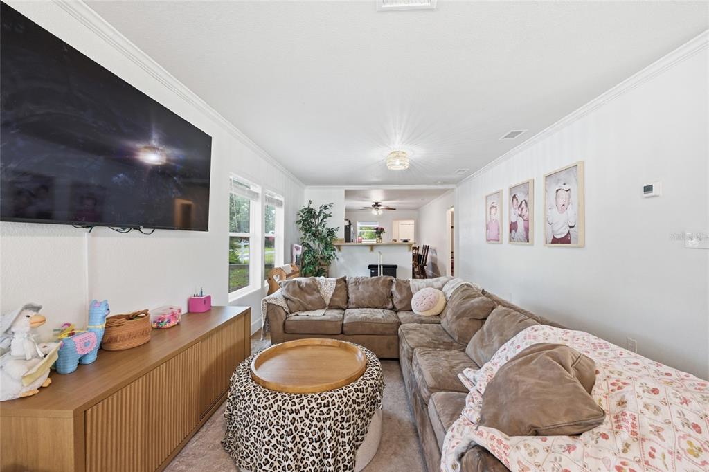 A living room features a large sectional sofa, a television, and a leopard-print ottoman — 5570 NAVARRE AVENUE, HAMPTON, FL