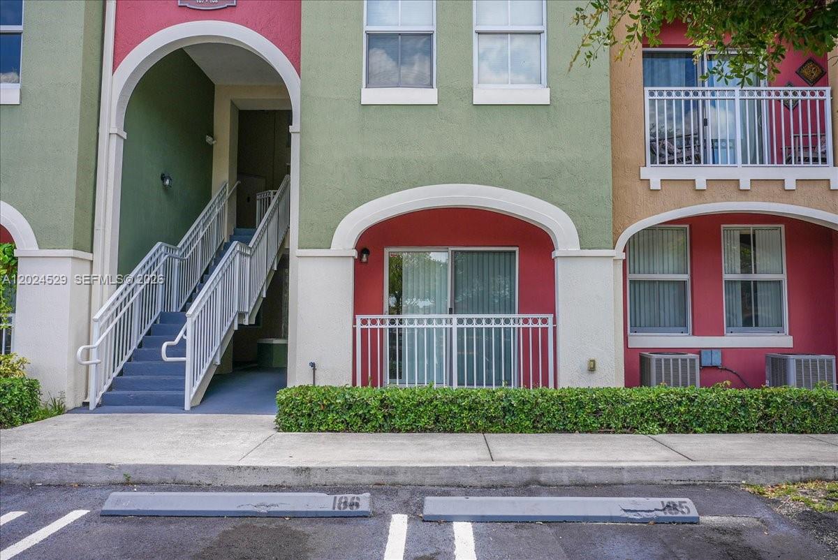 The exterior of a multi-story building features a staircase, a balcony, and parking spaces — 11102 NW 83rd St # 108, Doral FL 33178, DORAL, FL