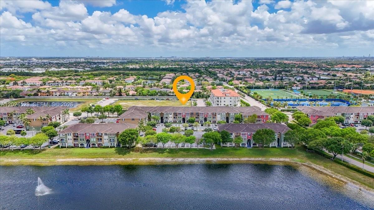 An aerial view shows a multi-story apartment complex situated beside a lake — 11102 NW 83rd St # 108, Doral FL 33178, DORAL, FL
