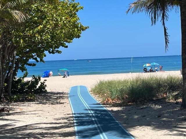 A blue beach access mat leads across the sand toward the ocean and beach umbrellas — 101 Briny Avenue # 2505, Pompano Beach FL 33062, POMPANO BEACH, FL
