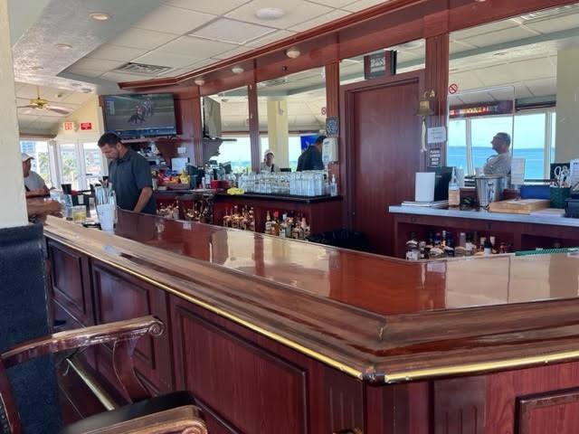A long, polished wooden bar with stools sits in a room overlooking the ocean — 101 Briny Avenue # 2505, Pompano Beach FL 33062, POMPANO BEACH, FL