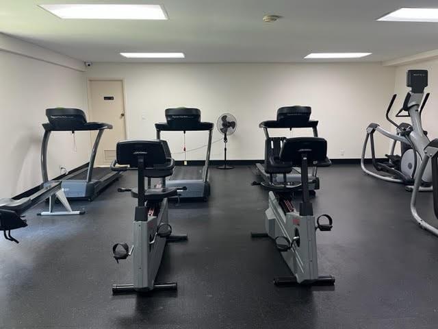 A gym room features several treadmills, stationary bikes, and an elliptical machine on a dark floor — 101 Briny Avenue # 2505, Pompano Beach FL 33062, POMPANO BEACH, FL