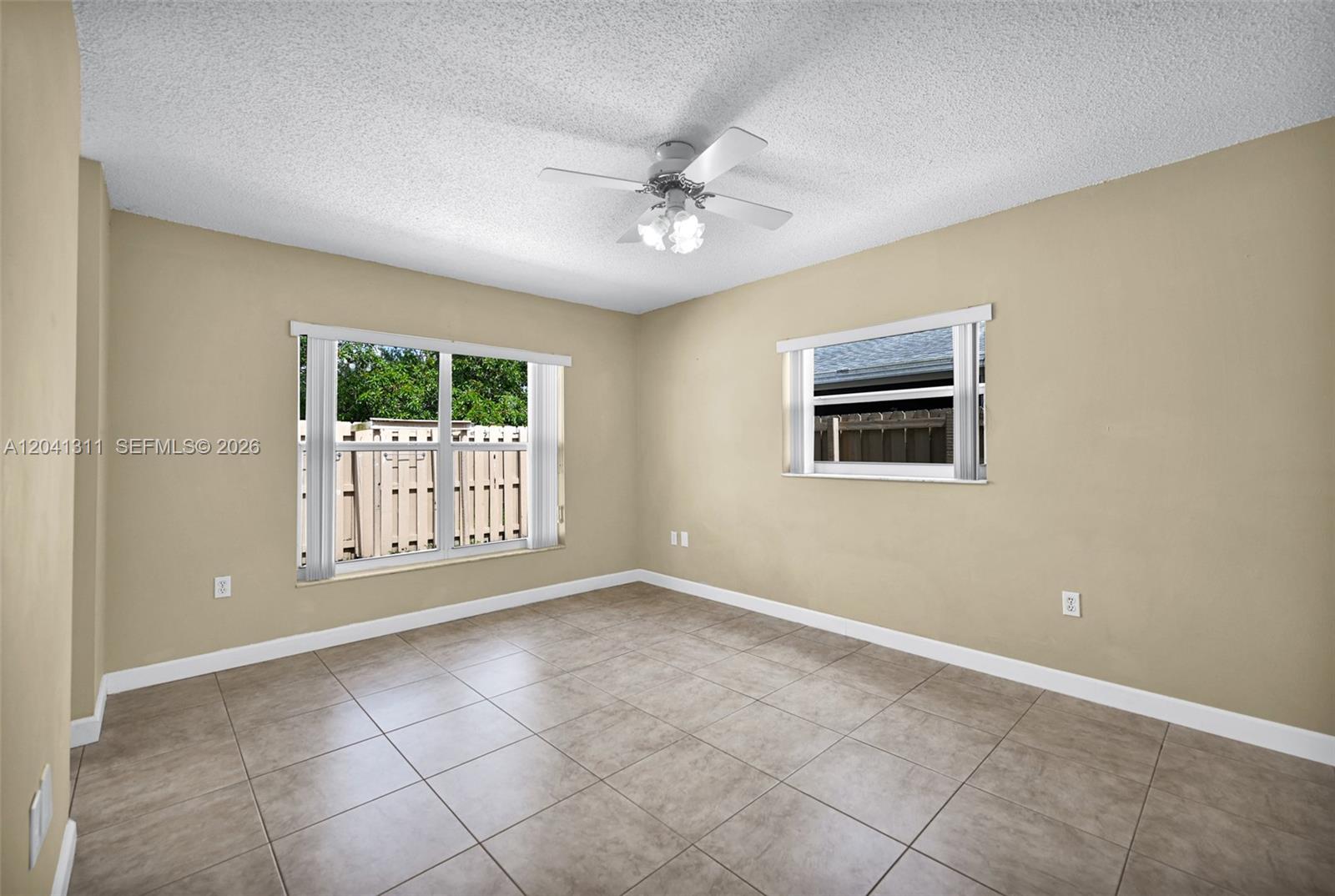 An empty bedroom features beige walls, tile flooring, a ceiling fan, and two windows — 4471 SW 138th Ct, Miami FL 33175, MIAMI, FL