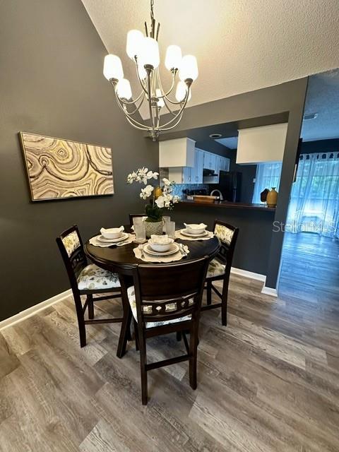 A dining area features a round wooden table, four chairs, and a chandelier under vaulted ceilings — 4833 MYRTLE OAK DRIVE UNIT 25, NEW PORT RICHEY, FL