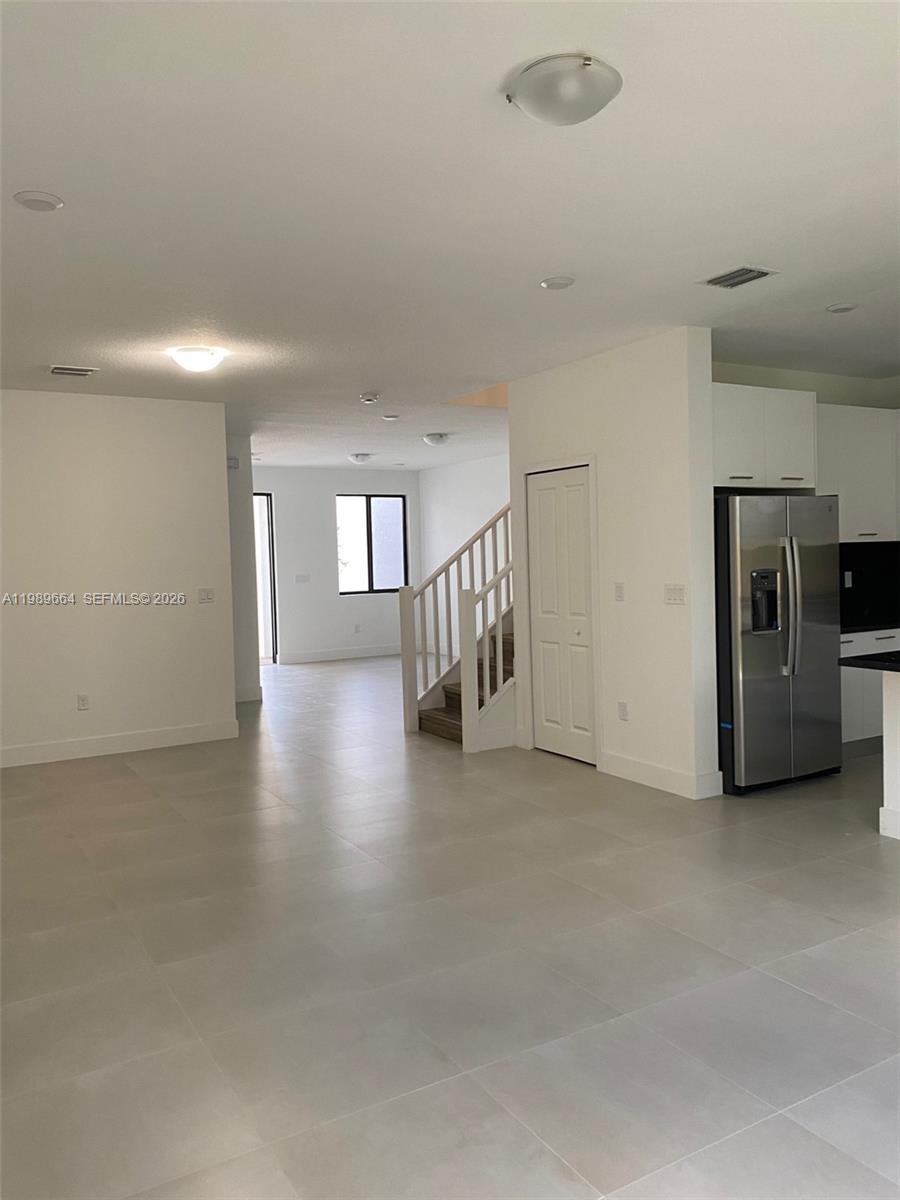 An open-concept living area features light tile flooring, a staircase, and a stainless steel refrigerator — 13633 SW 157th Pl # 0, Miami FL 33196, MIAMI, FL