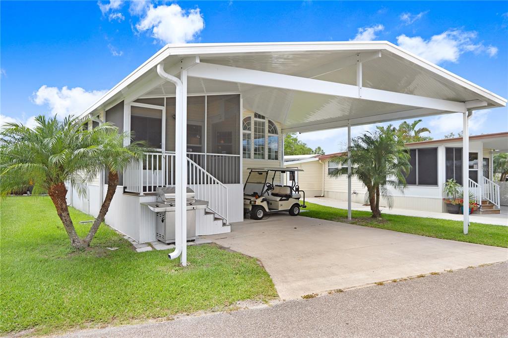 A mobile home with a screened-in porch, attached carport, and a golf cart parked underneath — 3333 26TH AVENUE E UNIT 1104, BRADENTON, FL
