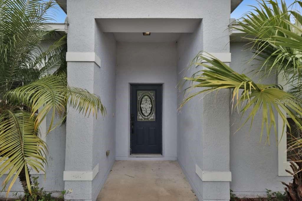 A covered entryway features a dark front door with a decorative glass insert — 820 GRANTHAM DRIVE, KISSIMMEE, FL