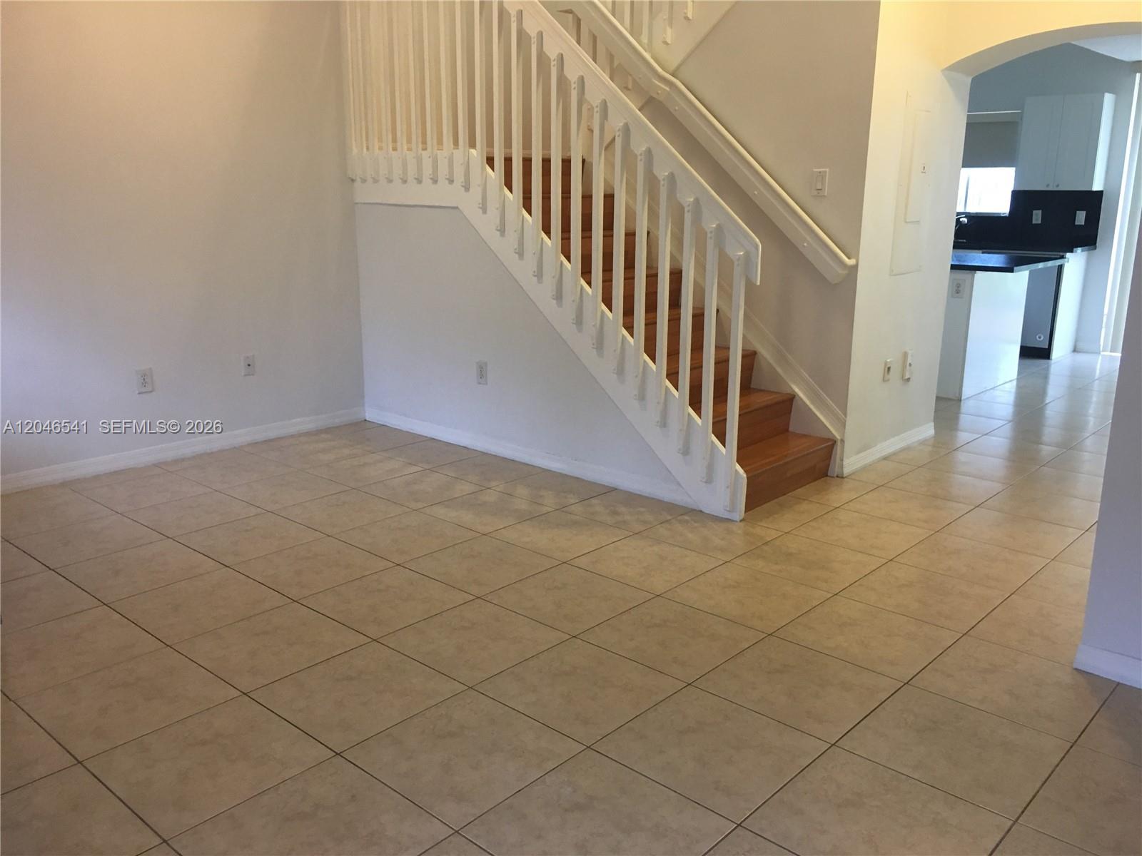 An interior view shows a tiled floor, a white staircase with wooden steps, and a kitchen — 11528 NW 60th Ter # 477, Doral FL 33178, DORAL, FL
