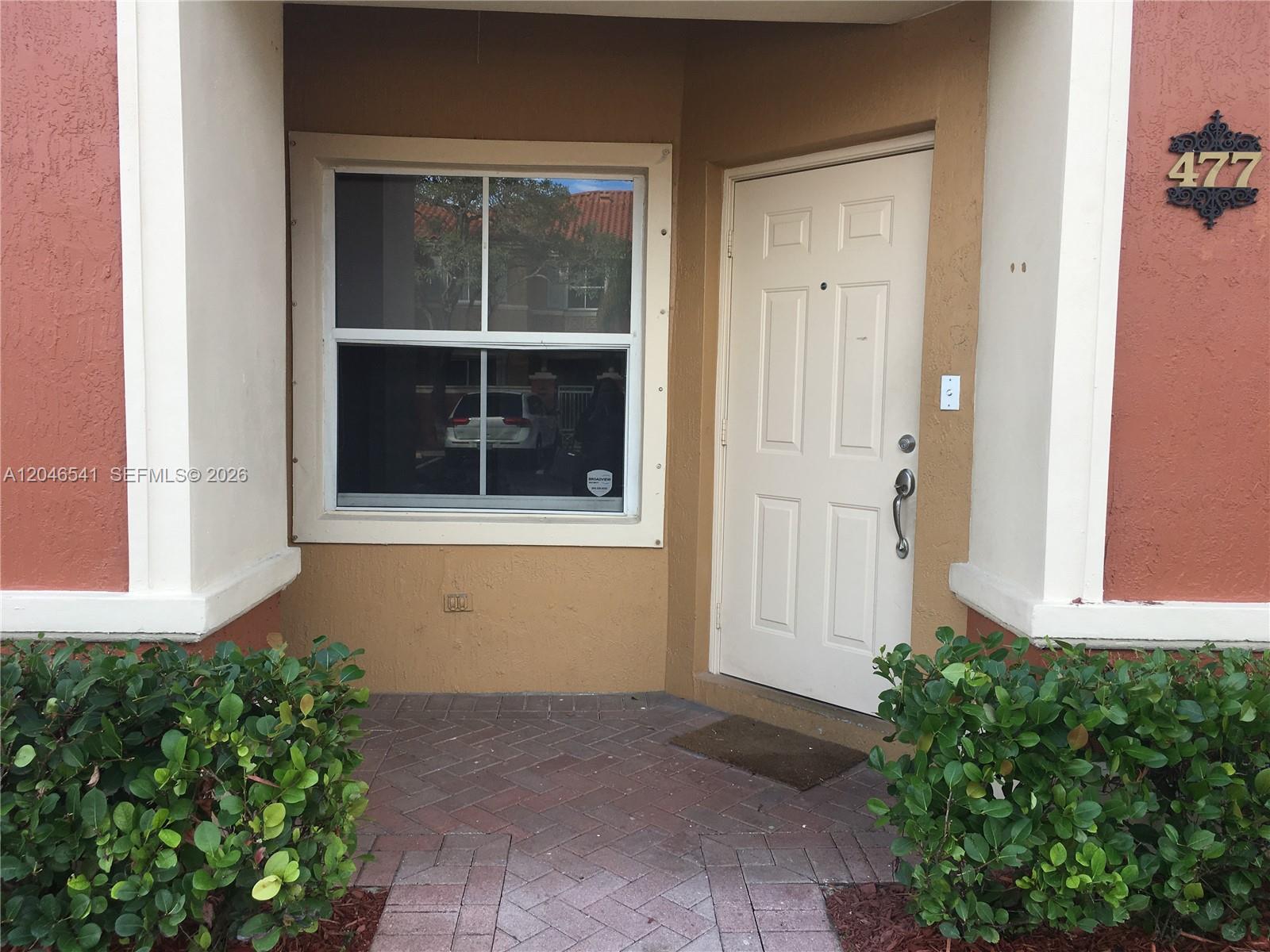 The exterior of a home features a tan wall, a window, and a white door — 11528 NW 60th Ter # 477, Doral FL 33178, DORAL, FL