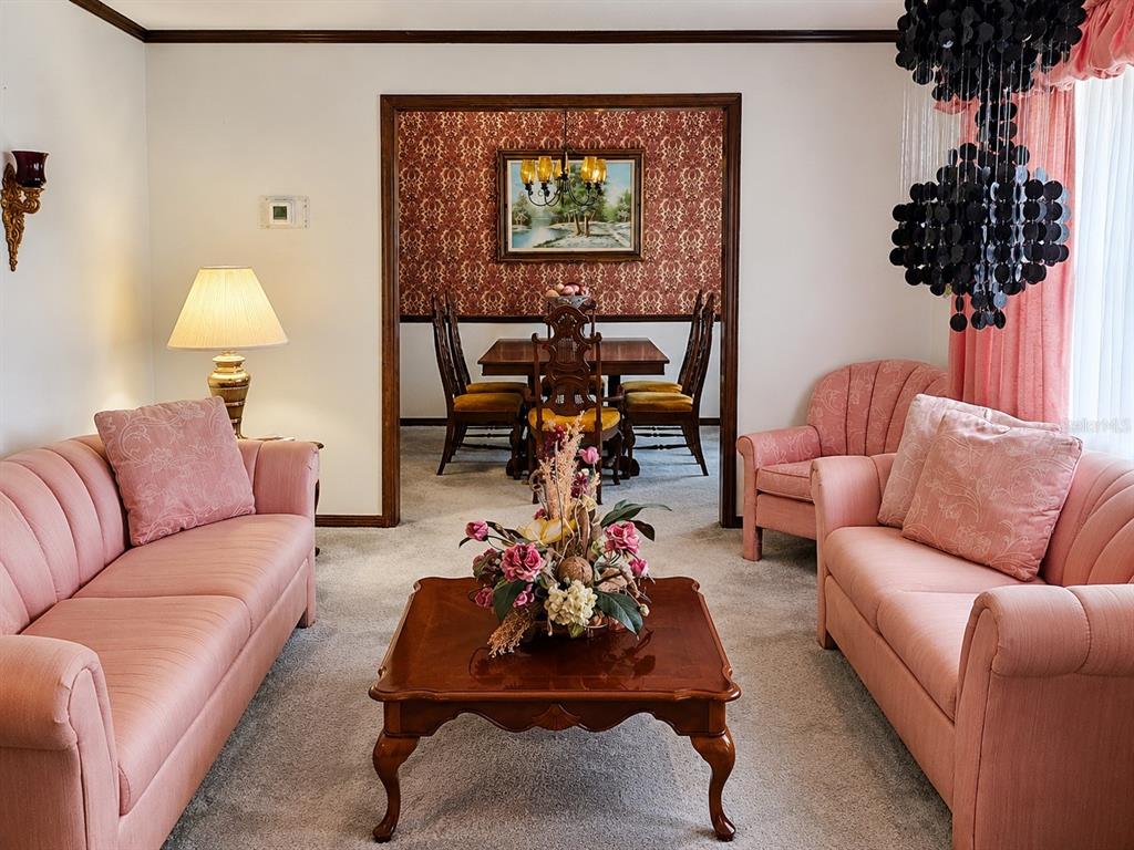 A living room with pink sofas faces a dining room with patterned wallpaper and furniture — 4303 KANDRA COURT, ORLANDO, FL