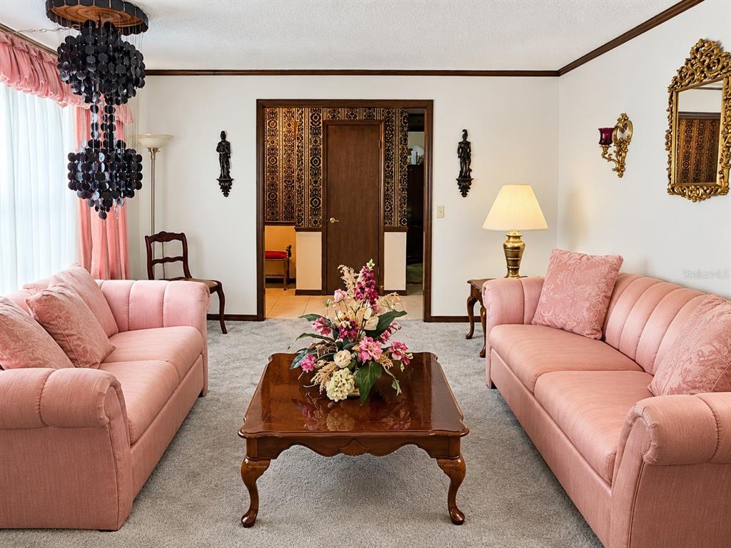 A living room features two pink sofas, a coffee table, and a dark chandelier — 4303 KANDRA COURT, ORLANDO, FL
