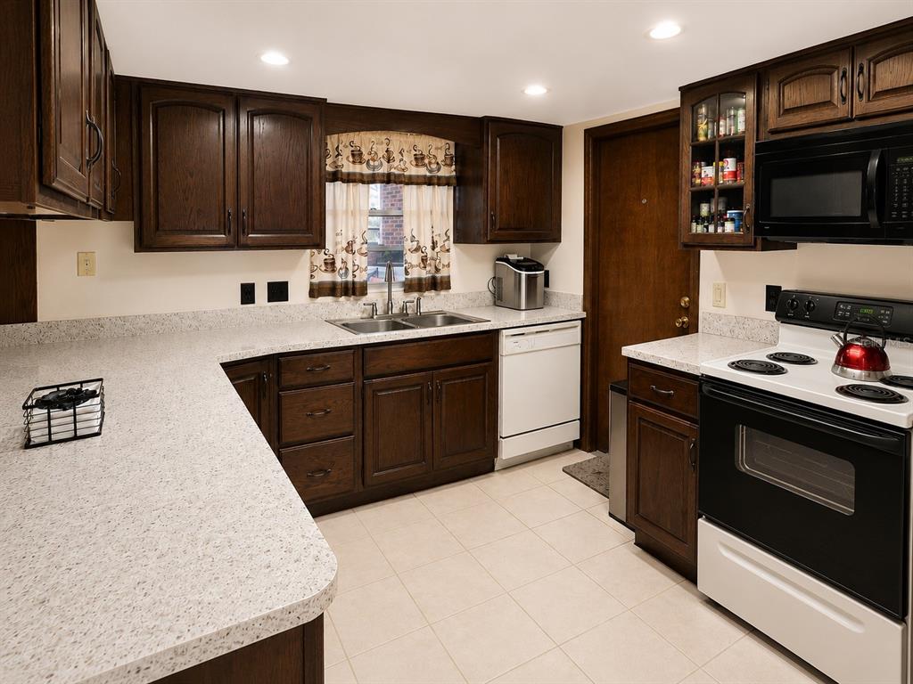 A kitchen features dark wood cabinets, light speckled countertops, white appliances, and tiled flooring — 4303 KANDRA COURT, ORLANDO, FL