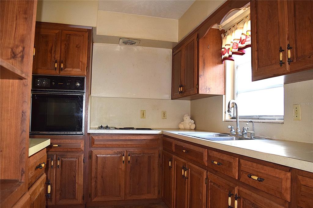 A kitchen features wood cabinets, a built-in oven, a cooktop, and a double-basin sink — 2535 BOSWELL STREET, DELTONA, FL