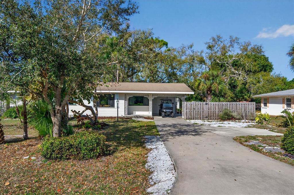 A single-story house with a concrete driveway, a carport, and mature trees in the yard — 6338 BEECHWOOD AVENUE, SARASOTA, FL