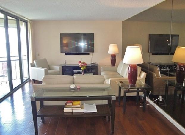A living room features a glass-topped console table, a sofa, and a wall-mounted television — 5729 PUERTA DEL SOL BOULEVARD S UNIT 485, ST PETERSBURG, FL