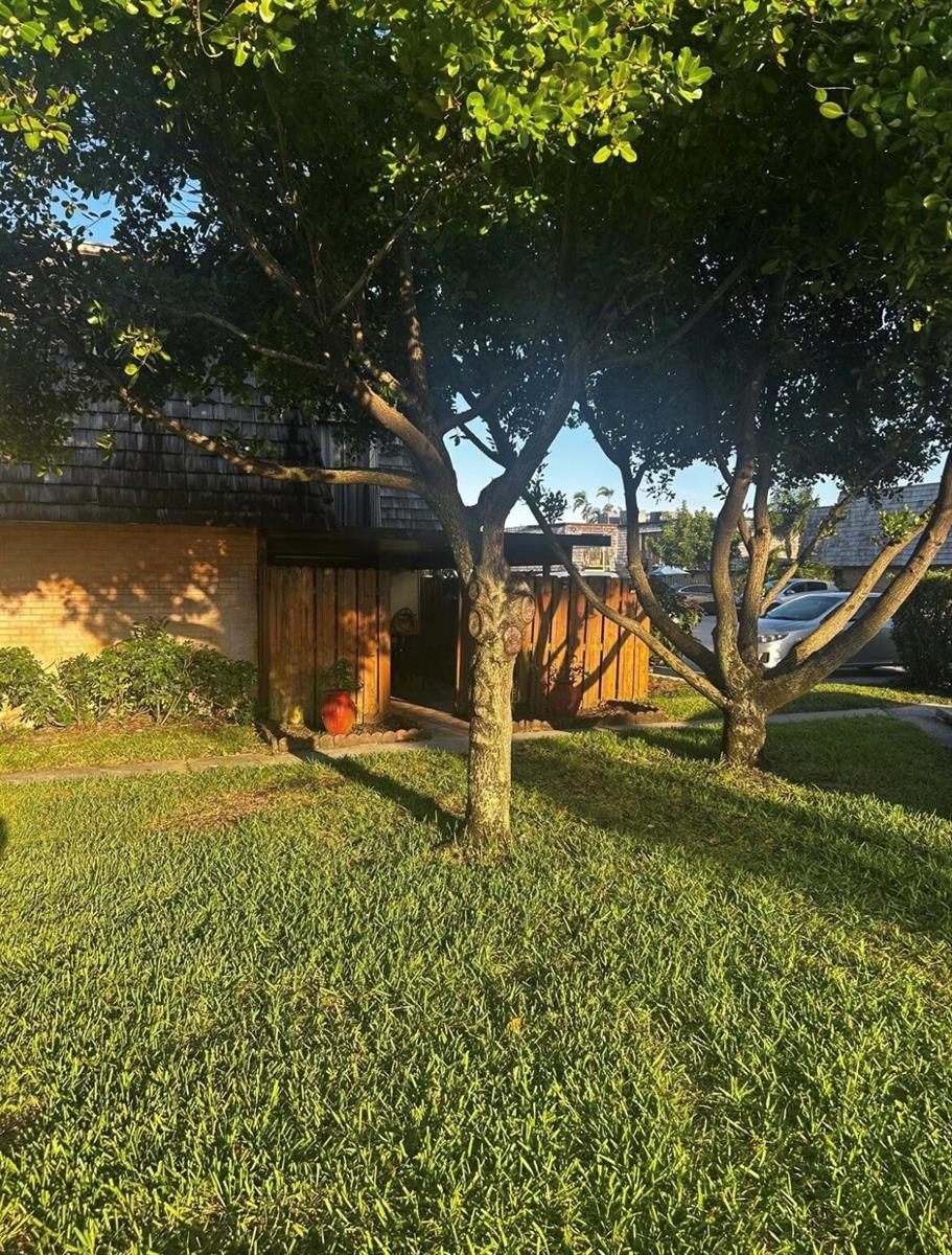 A wooden privacy fence stands in front of a building exterior with mature trees — 341 Lake Arbor Drive, Palm Springs FL 33461, PALM SPRINGS, FL