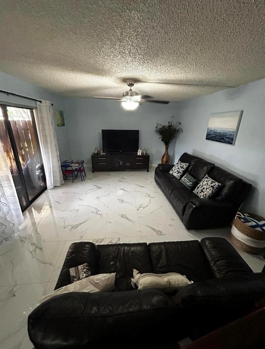 A living room features light blue walls, white marble-look tile flooring, and two black leather sofas — 341 Lake Arbor Drive, Palm Springs FL 33461, PALM SPRINGS, FL