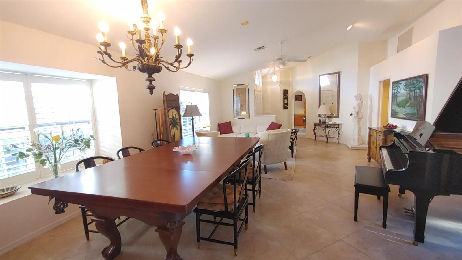 A dining room with a large wooden table, chandelier, and a grand piano nearby — 16461 Riverwind Drive, Jupiter FL 33477, JUPITER, FL