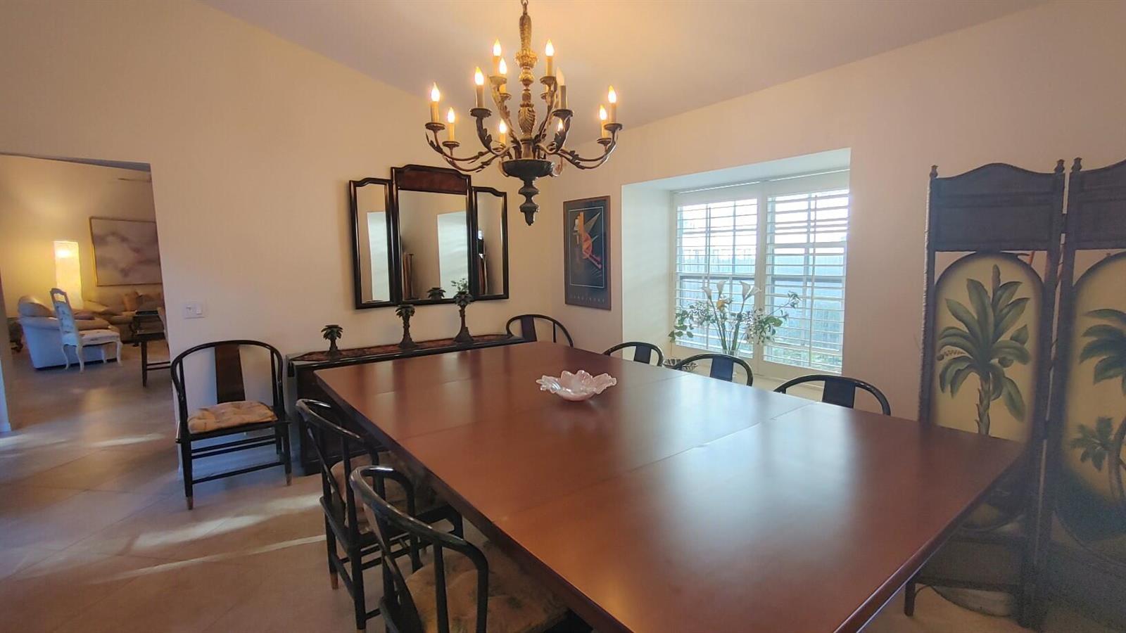 A dining room features a large wooden table, a chandelier, and a tri-fold mirror — 16461 Riverwind Drive, Jupiter FL 33477, JUPITER, FL