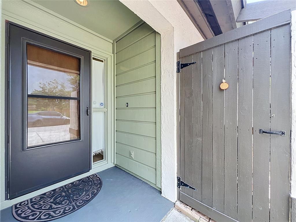A front entryway features a dark storm door, green horizontal siding, and a wooden privacy gate — 2305 SUN VALLEY CIR, WINTER PARK, FL 32792, WINTER PARK, FL