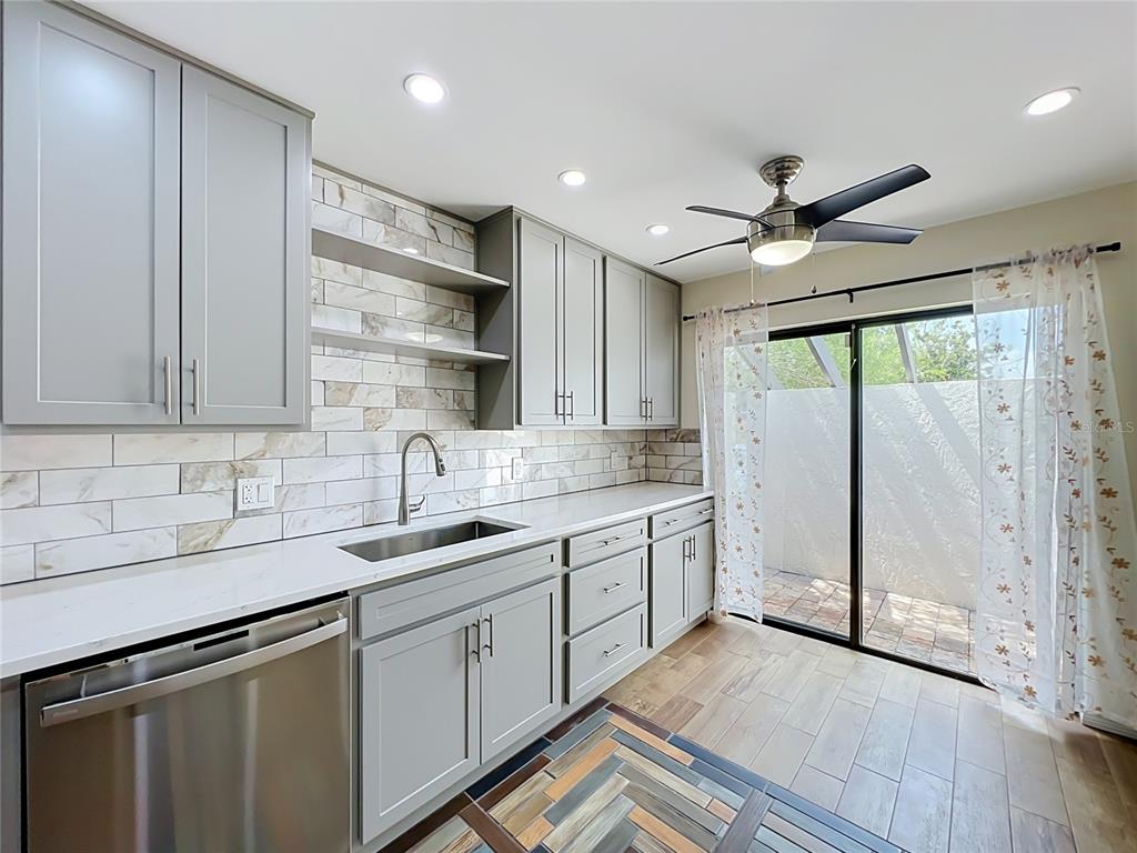A kitchen features gray cabinets, white countertops, a tiled backsplash, and a sliding glass door — 2305 SUN VALLEY CIR, WINTER PARK, FL 32792, WINTER PARK, FL