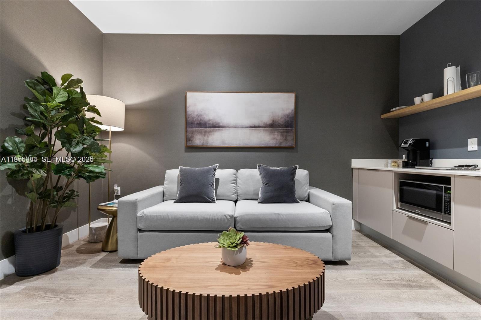 A modern living room features a light gray sofa, a round wooden coffee table, and cabinetry — 229 SW 9th St # 705, Miami FL 33130, MIAMI, FL