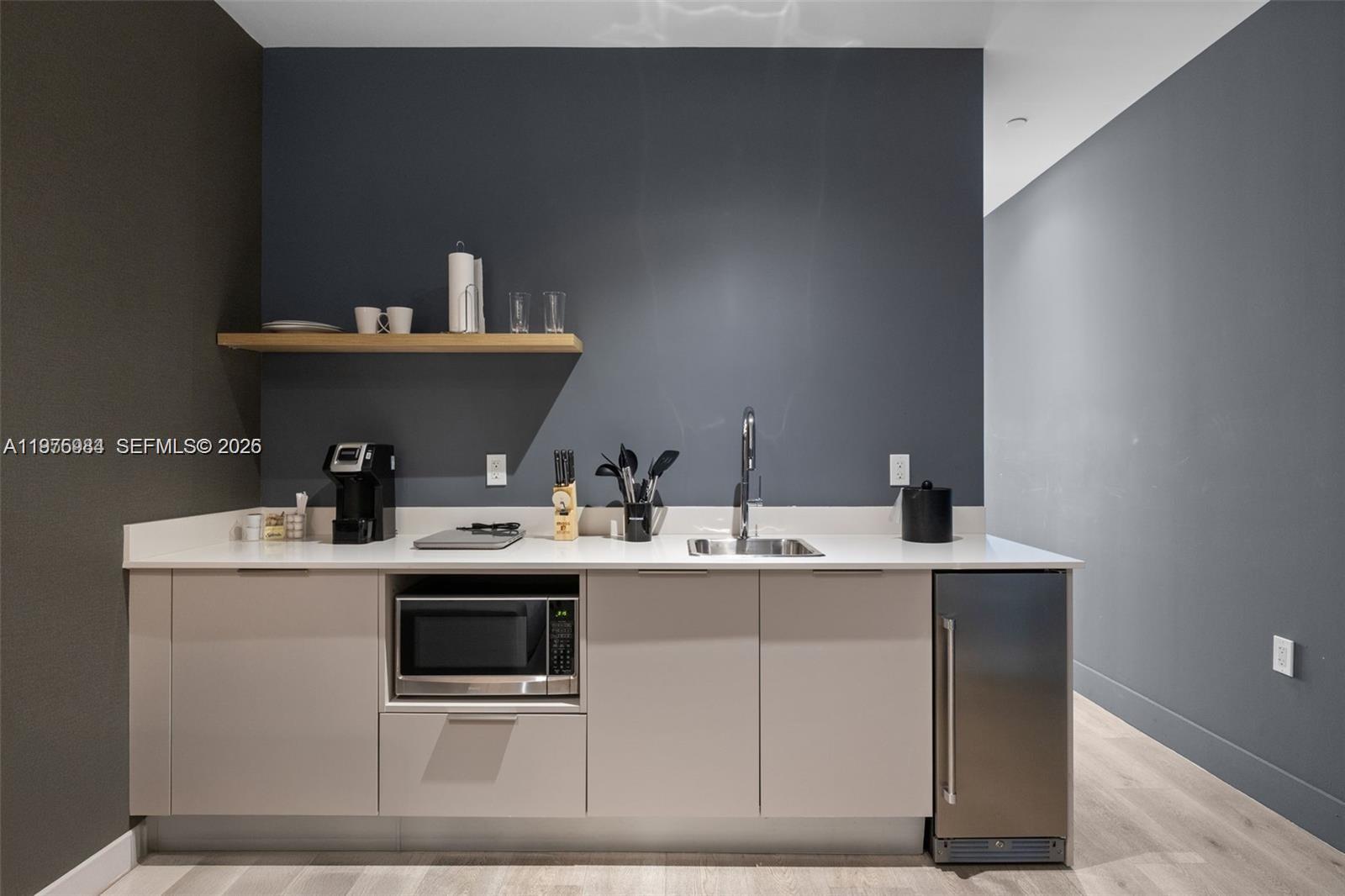 A kitchenette features light-colored cabinets, a stainless steel microwave, a sink, and a floating shelf — 229 SW 9th St # 705, Miami FL 33130, MIAMI, FL