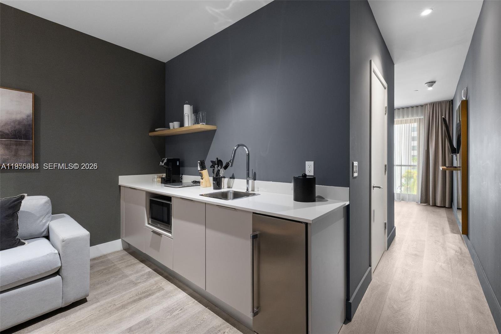 A kitchenette with a sink, microwave, and small refrigerator sits against a dark gray wall — 229 SW 9th St # 705, Miami FL 33130, MIAMI, FL