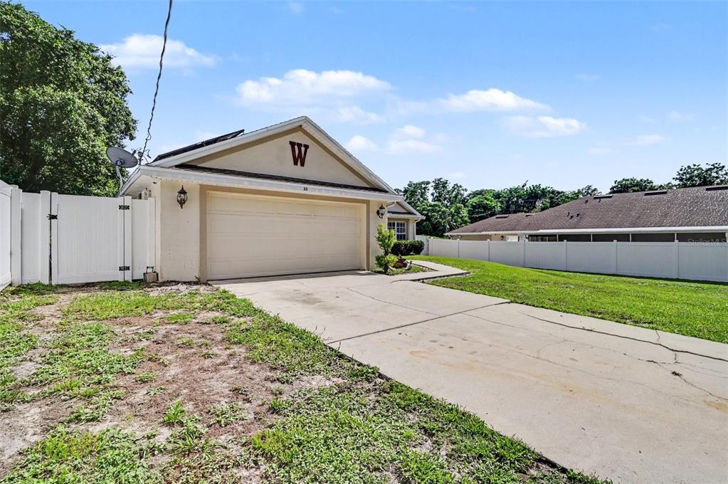 A detached garage with a white vinyl fence and a concrete driveway in a yard — 35 PLANTATION ROAD, DEBARY, FL